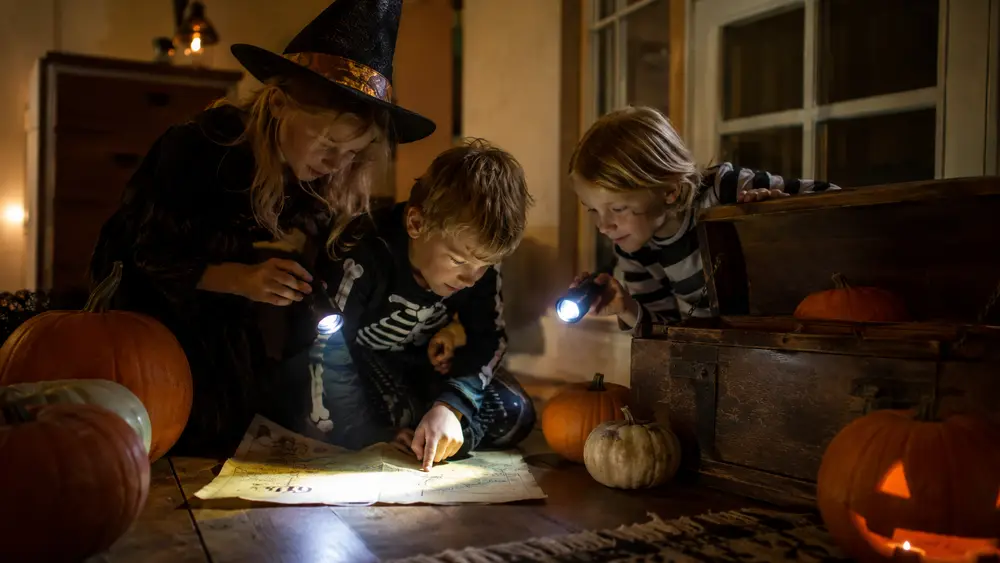 Halloween-speurtocht voor kinderen: Foto: verklede kinderen met zaklampjes zoeken aanwijzingen tussen pompoenen