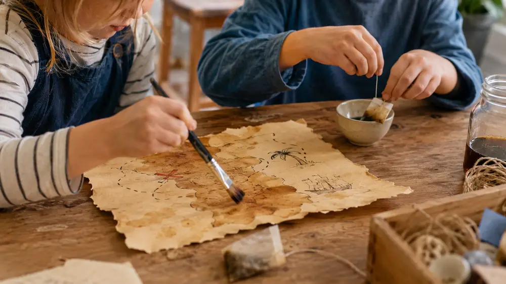 Met thee vergeelde, oud gemaakte schatkaart droogt op tafel met een penseel ernaast