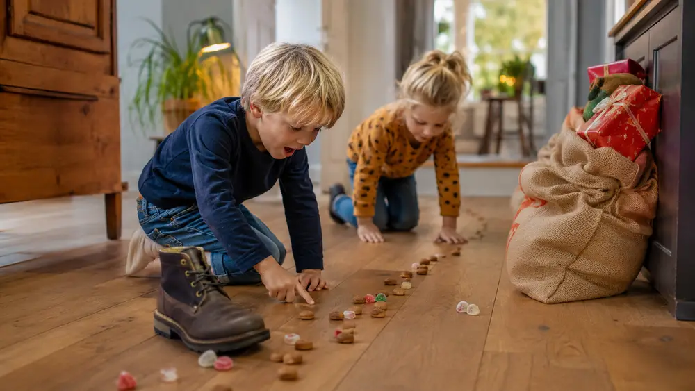 Sinterklaas-speurtocht voor kinderen: Foto: kinderen volgen een spoor van pepernoten naar een zak met cadeautjes